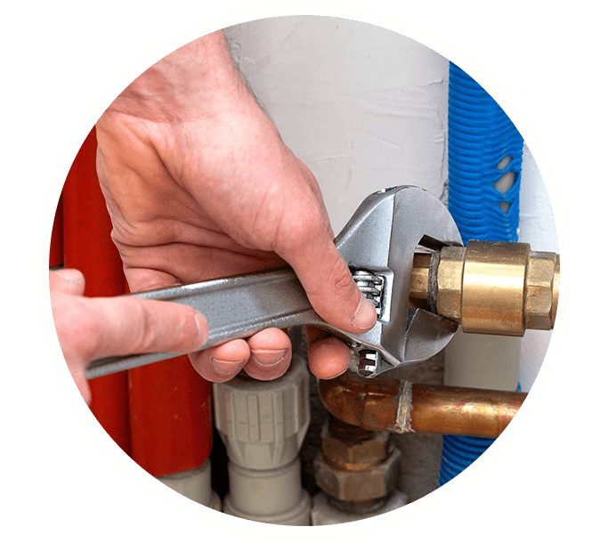 A person is working on the pipes of a water heater.